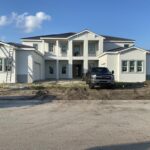 Newly constructed large two-story home with smooth stucco finish, featuring clean lines and modern architectural details.