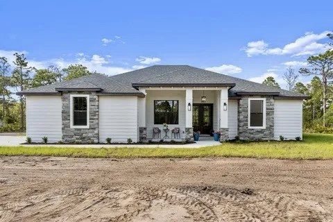 “Modern Florida home with smooth white stucco exterior, gray stone accents, and black roof — designed and finished by Bell’s Creative Design Stucco for lasting curb appeal and weather resistance.”